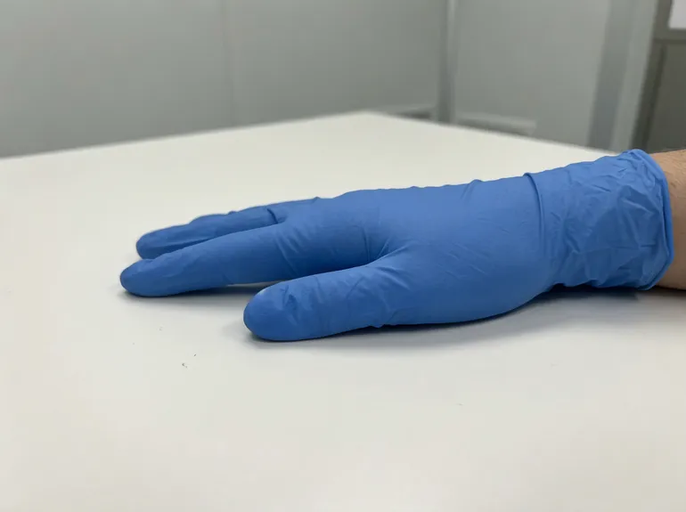 Blue nitrile glove contrasting against clinical surface for contamination visibility