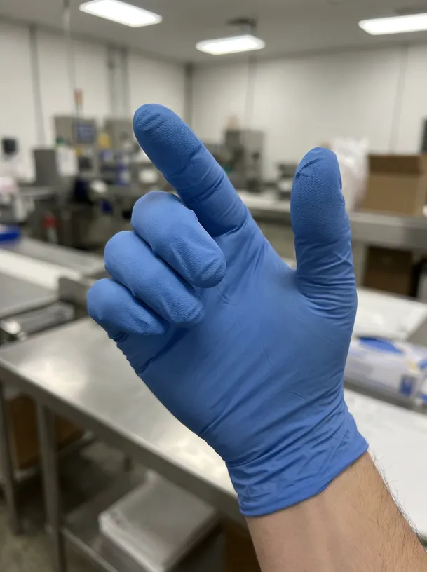 Close-up detail of powder free blue nitrile glove showing textured fingertip surface finish